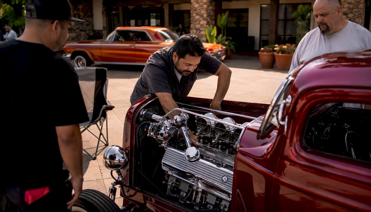 Enthusiast inspecting vintage hot rod outdoors