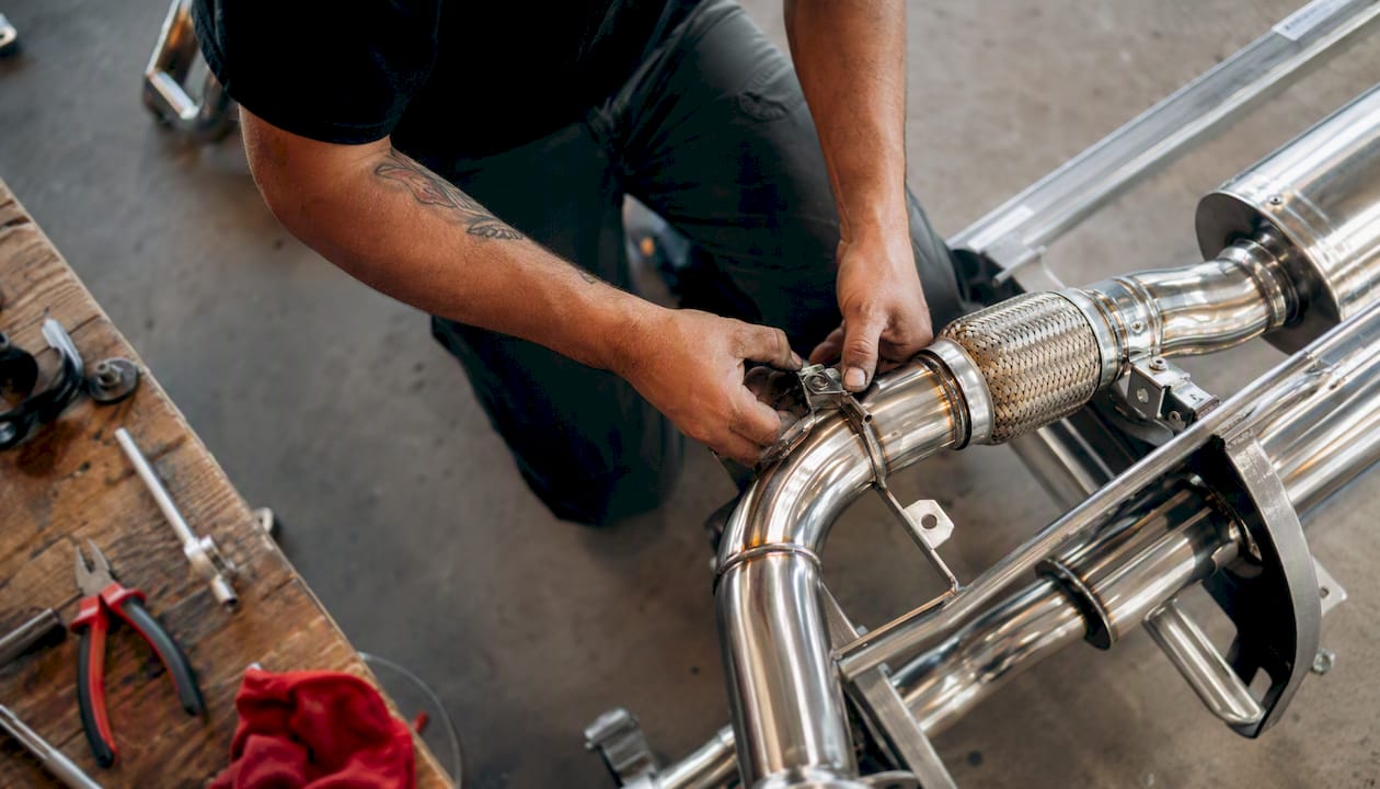 Hands tightening clamps on stainless exhaust muffler