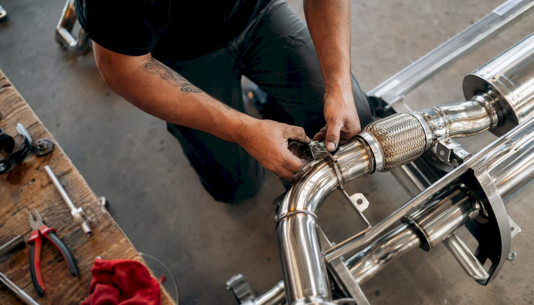Hands tightening clamps on stainless exhaust muffler