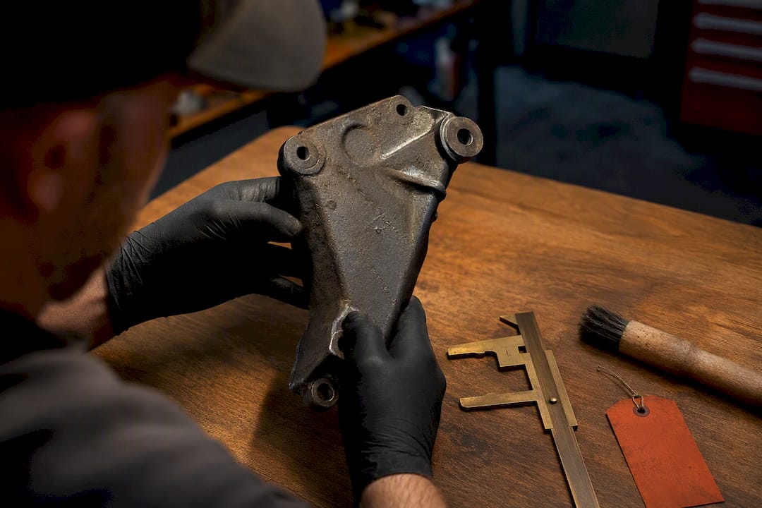 Gloved hand examining stamped vehicle bracket